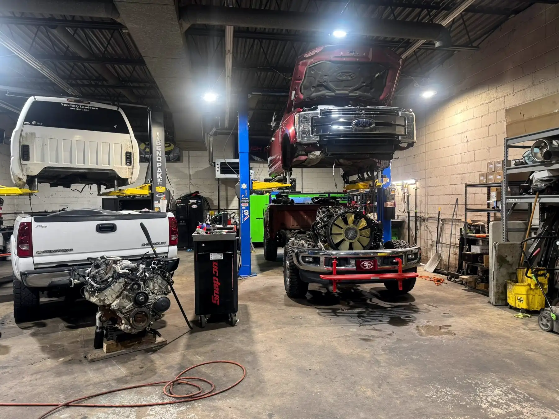 CBS Diesel shop floor with a diesel engine on a stand in front of a truck on a lift